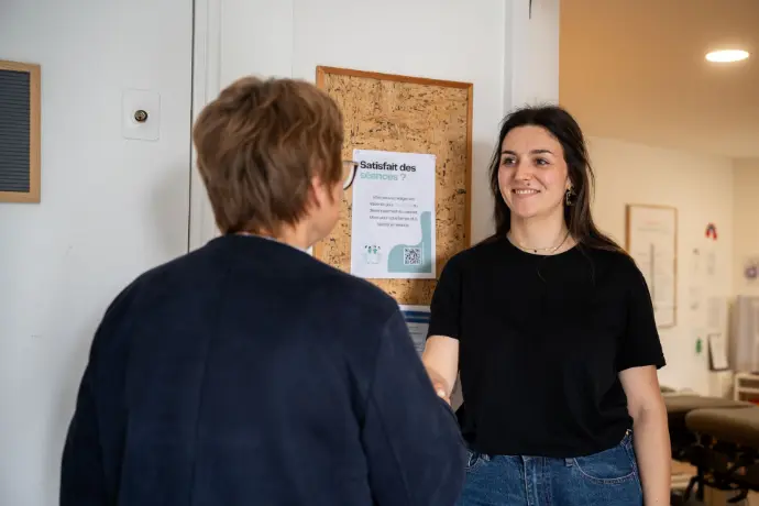 Chiropracteur accueillant une patiente devant le cabinet à Verfeill
